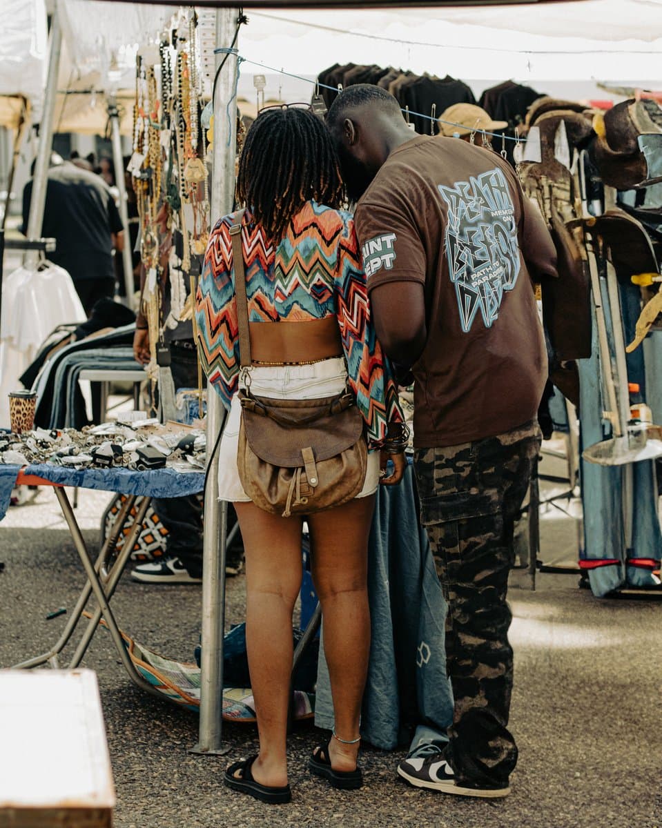A vendor and a shopper talking over a rail of clothing